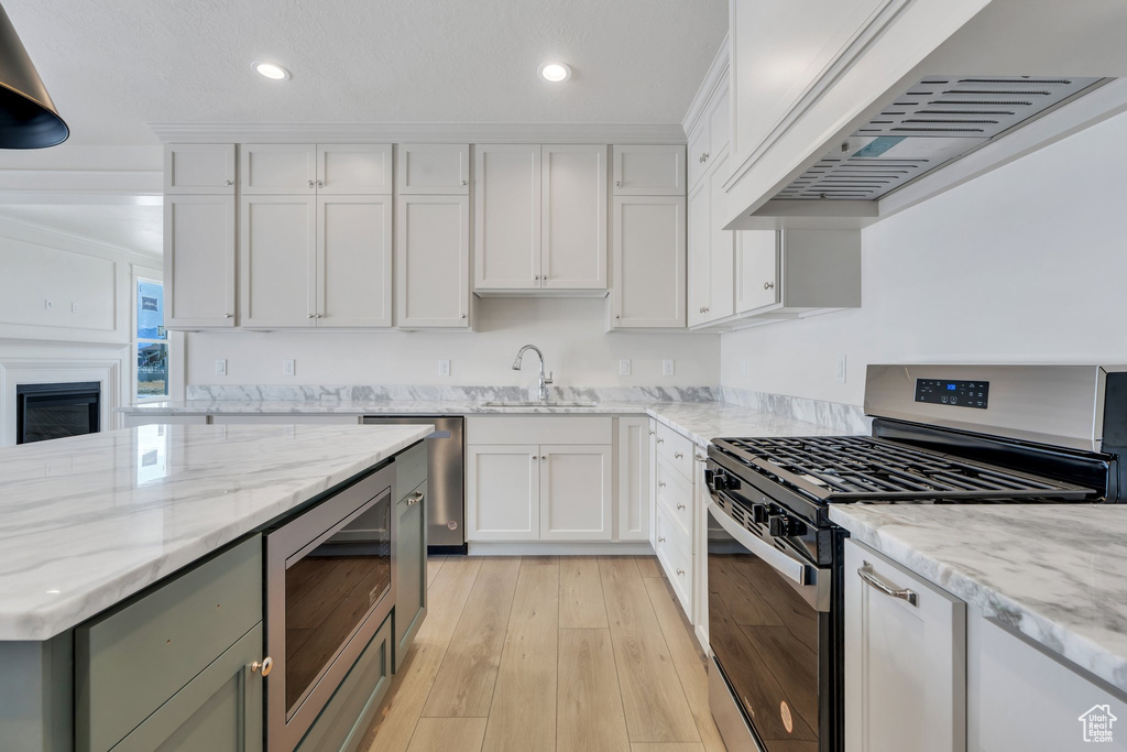 Kitchen featuring appliances with stainless steel finishes, extractor fan, white cabinetry, and recessed lighting