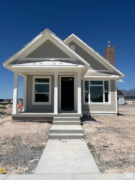 View of front of property featuring covered porch and a chimney