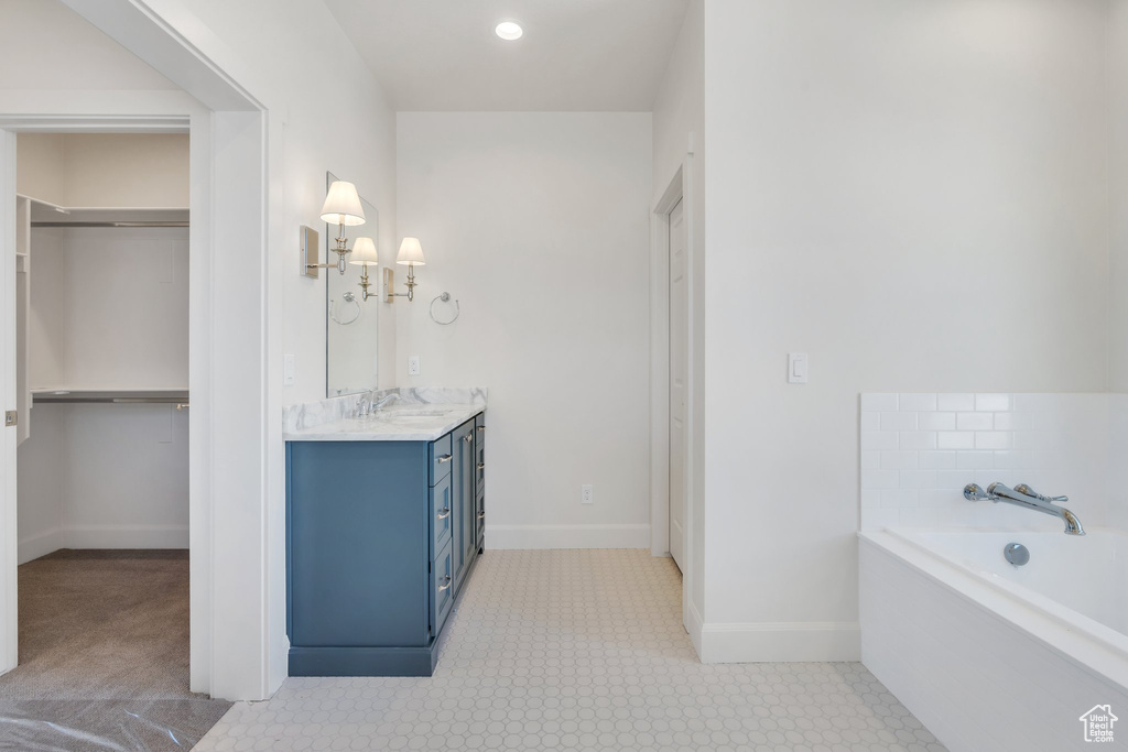 Bathroom featuring vanity, a garden tub, and a walk in closet