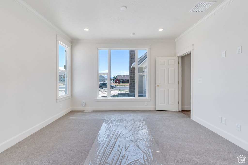 Carpeted empty room with ornamental molding, healthy amount of natural light, and recessed lighting