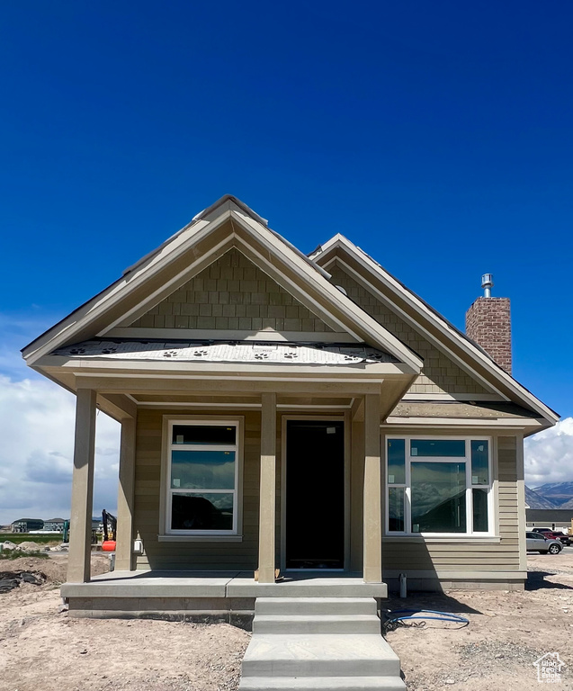 View of front of home with covered porch and a chimney