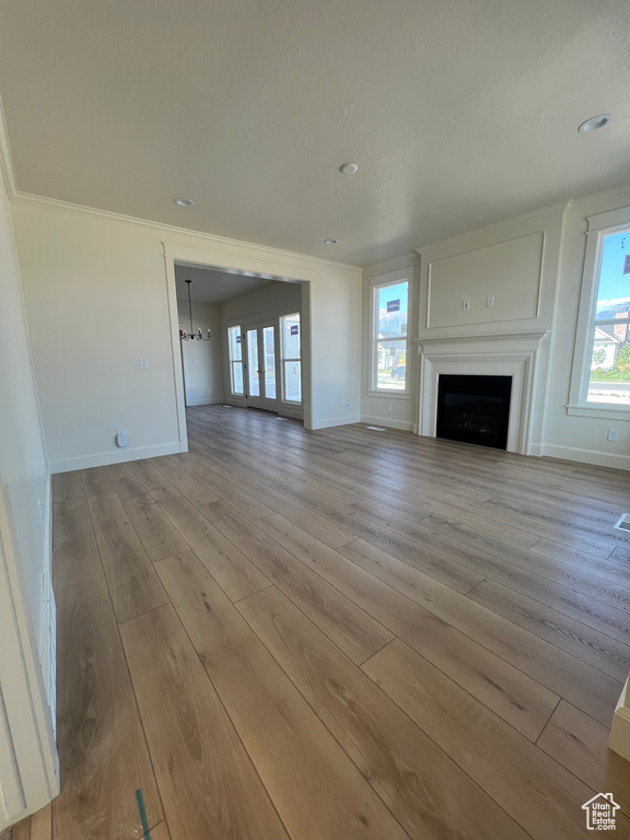Unfurnished living room with wood finished floors, baseboards, a fireplace, crown molding, and recessed lighting