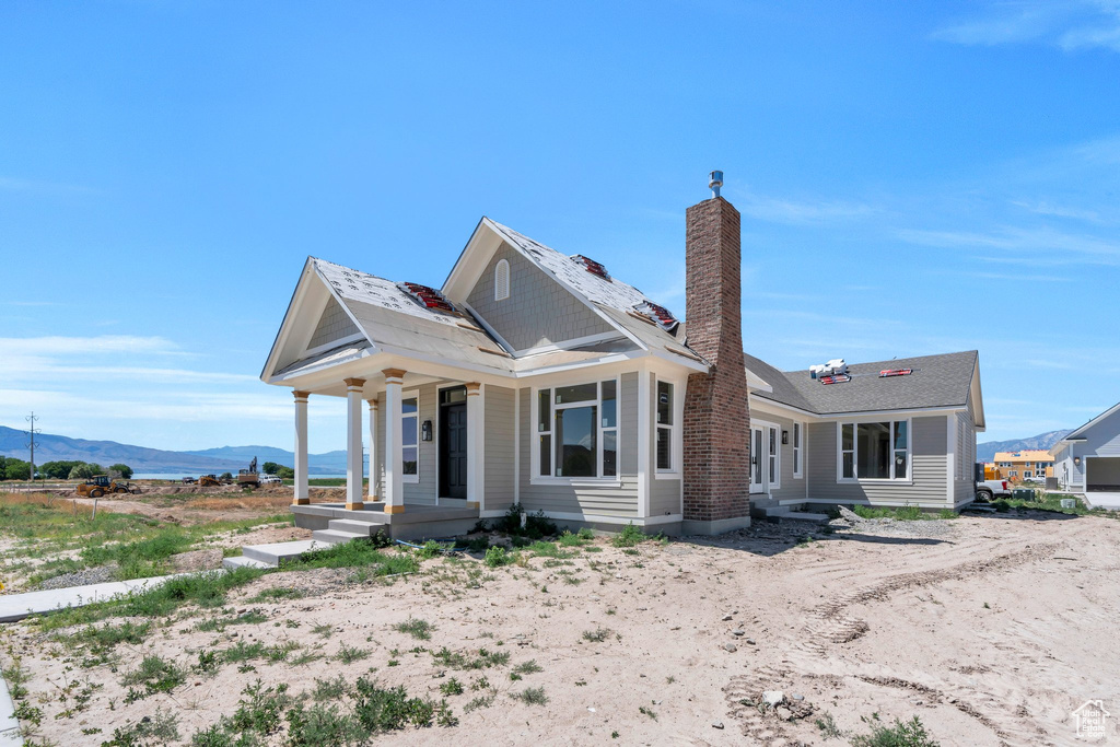 View of front of home with a mountain view, covered porch, and a chimney