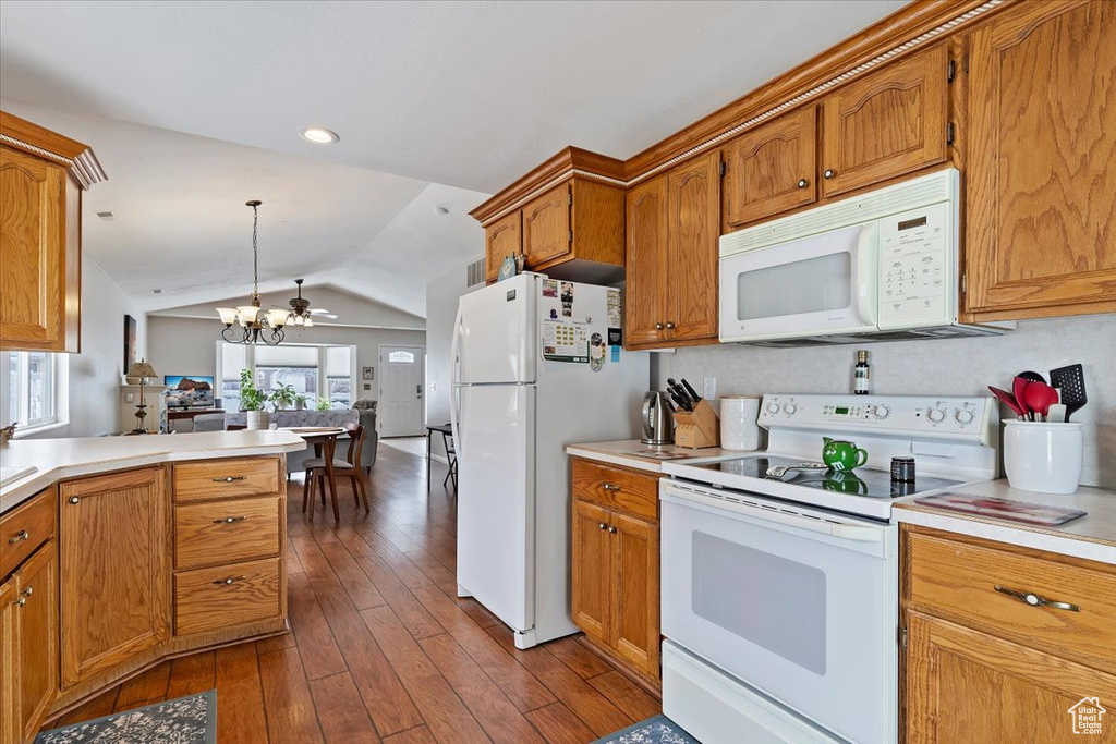 Kitchen with brown cabinetry, white appliances, light countertops, and decorative light fixtures