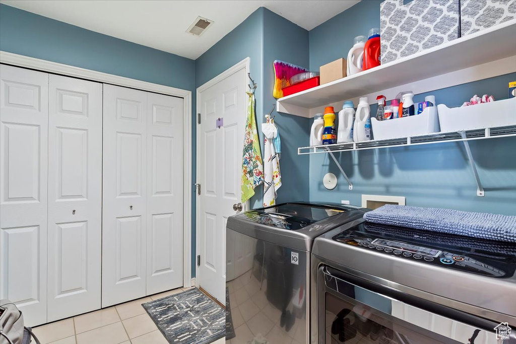 Washroom featuring laundry area, visible vents, washer and dryer, and light tile patterned flooring