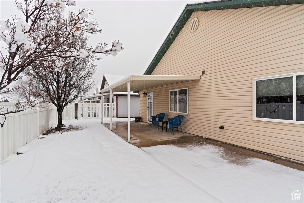 Snow covered rear of property with a fenced backyard