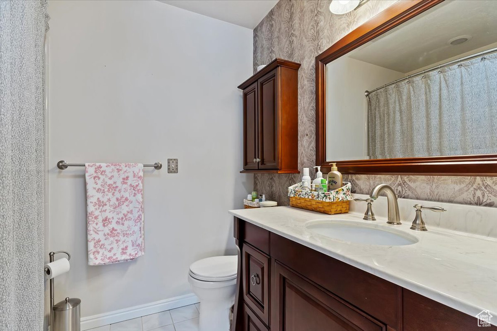 Bathroom featuring toilet, tile patterned floors, baseboards, and vanity
