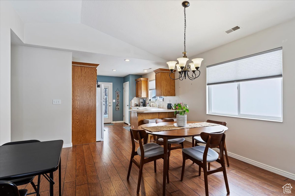 Dining space with visible vents, a chandelier, vaulted ceiling, and dark wood-style flooring
