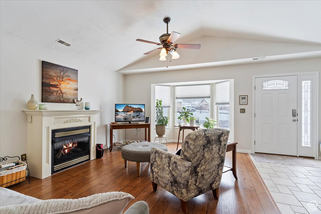 Living area featuring lofted ceiling, a healthy amount of sunlight, visible vents, and wood finished floors