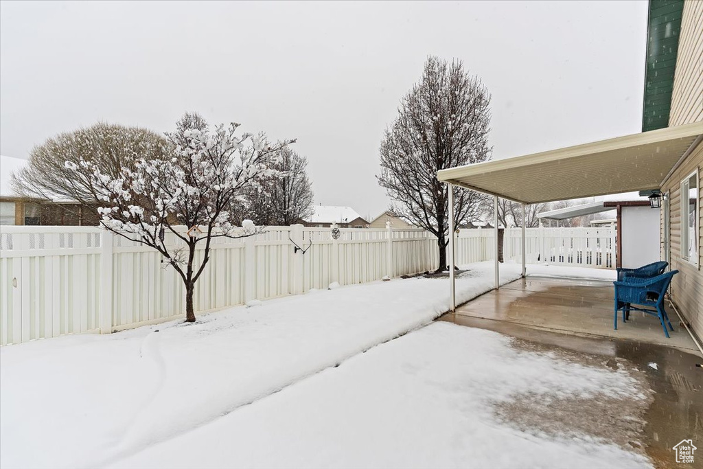 Snowy yard with a fenced backyard and a patio