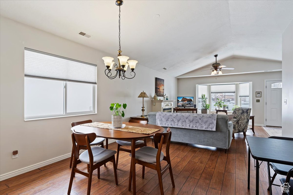 Dining space with visible vents, vaulted ceiling, baseboards, and dark wood finished floors
