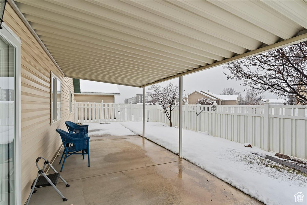 Snow covered patio with a fenced backyard