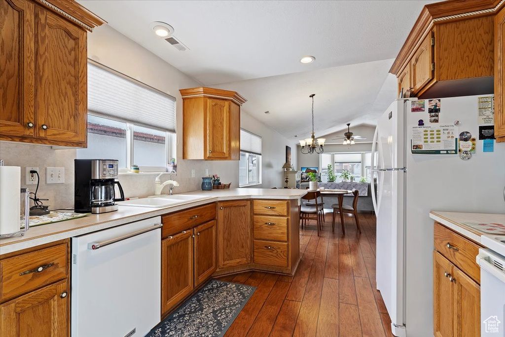 Kitchen with white appliances, a sink, light countertops, brown cabinets, and pendant lighting