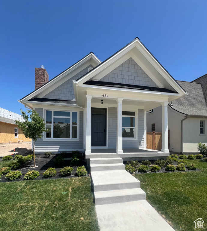 View of front of home with a chimney, a front lawn, and covered porch