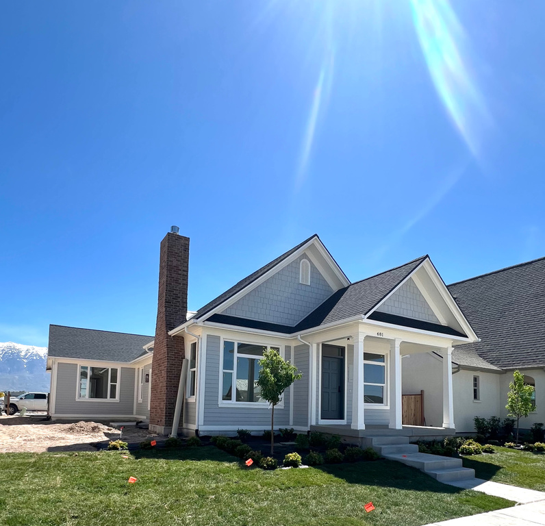 Ranch-style house featuring covered porch, a chimney, and a front yard