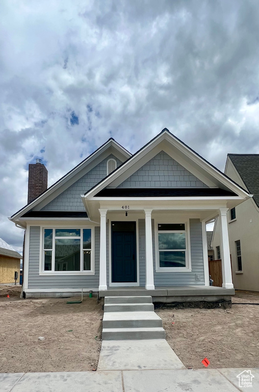 View of front of house with a chimney and covered porch