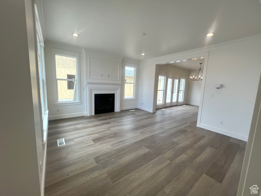 Unfurnished living room with an inviting chandelier, baseboards, and visible vents