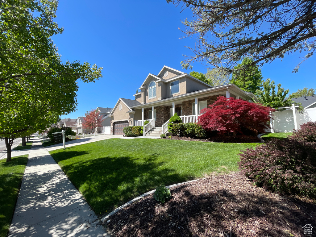Traditional-style home with covered porch, stone siding, concrete driveway, and a residential view