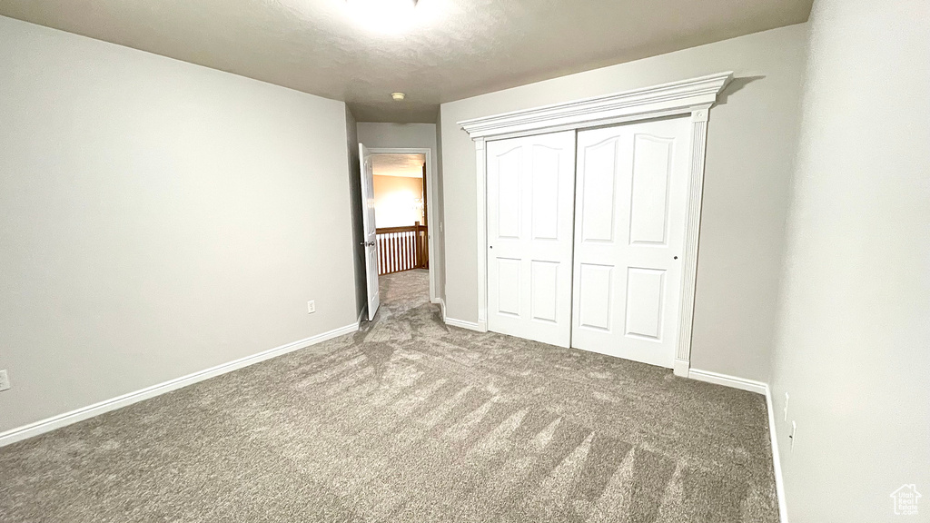 Unfurnished bedroom featuring carpet floors, a closet, and baseboards