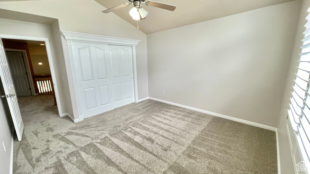 Unfurnished bedroom featuring carpet flooring, baseboards, a closet, lofted ceiling, and a ceiling fan