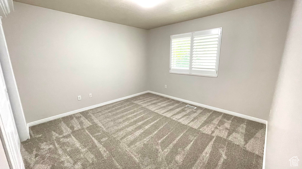 Empty room featuring carpet flooring and baseboards