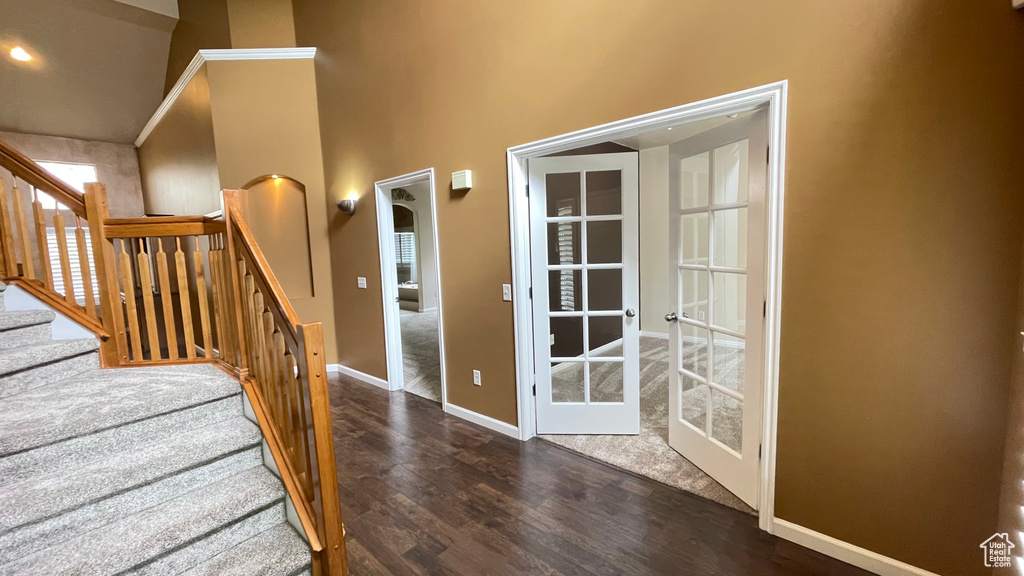 Staircase with wood finished floors, baseboards, french doors, and a towering ceiling