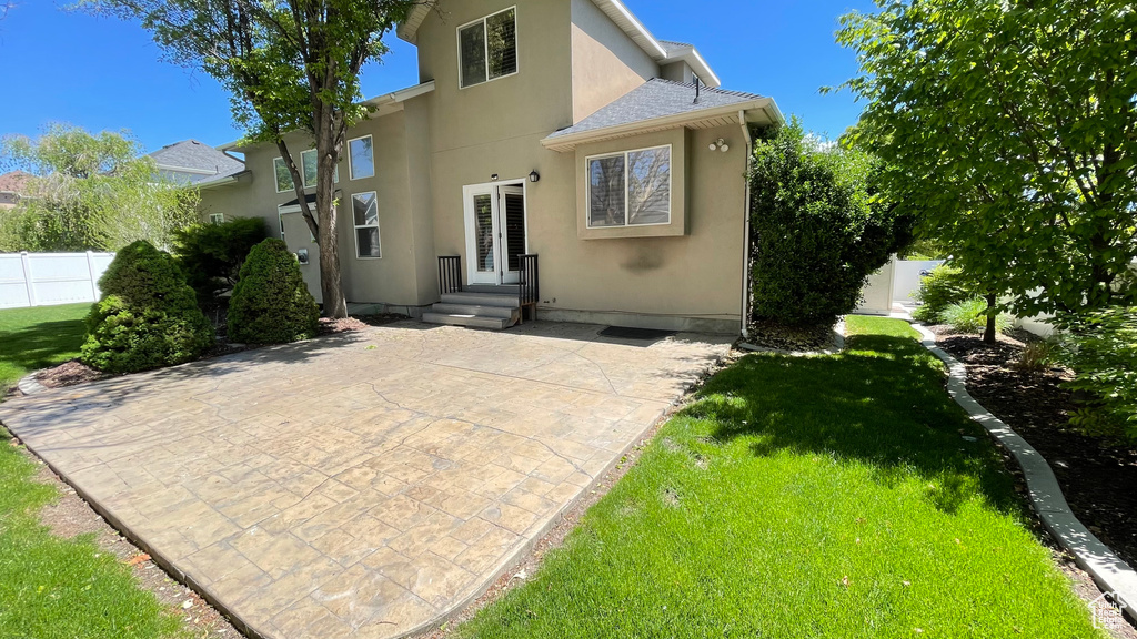 Rear view of house with stucco siding, a patio, and a shingled roof