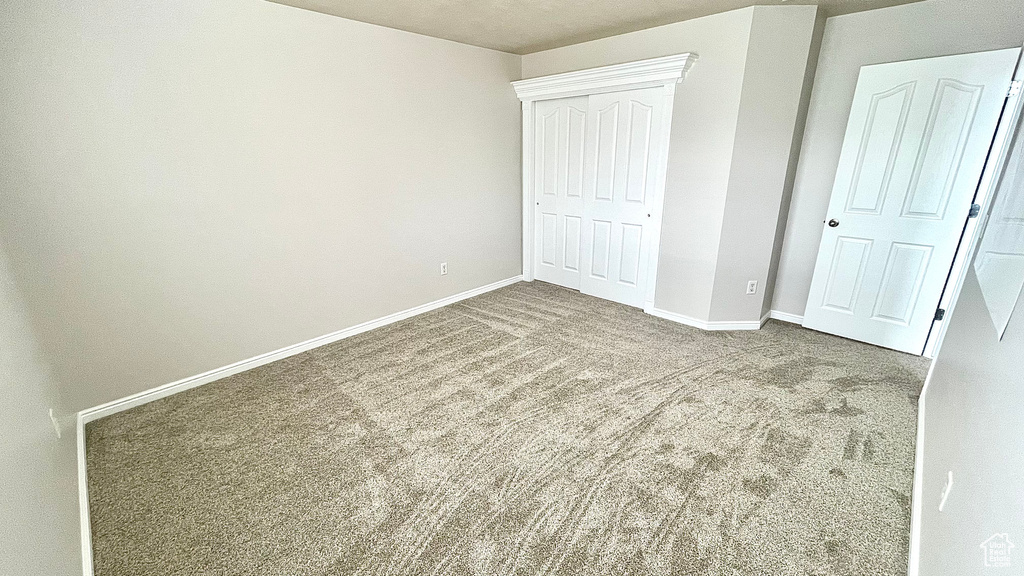 Unfurnished bedroom featuring carpet, baseboards, and a closet