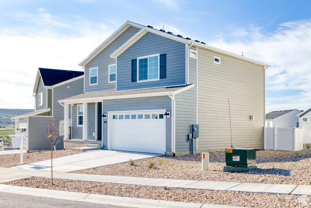 View of front of property featuring an attached garage, fence, and driveway