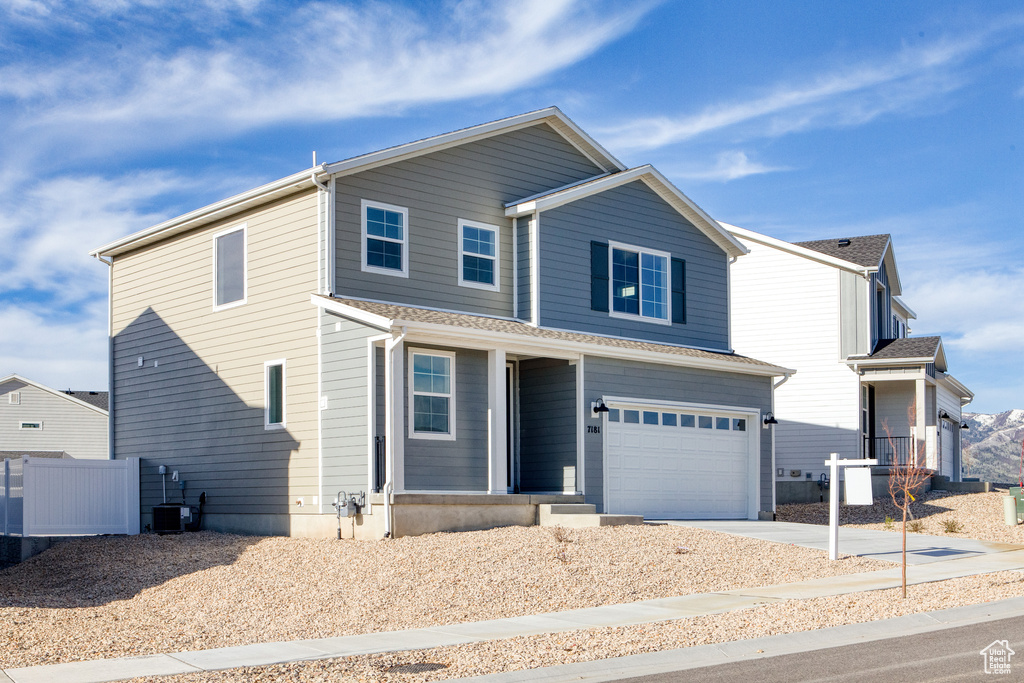 Traditional-style home with an attached garage, driveway, a porch, central AC unit, and fence