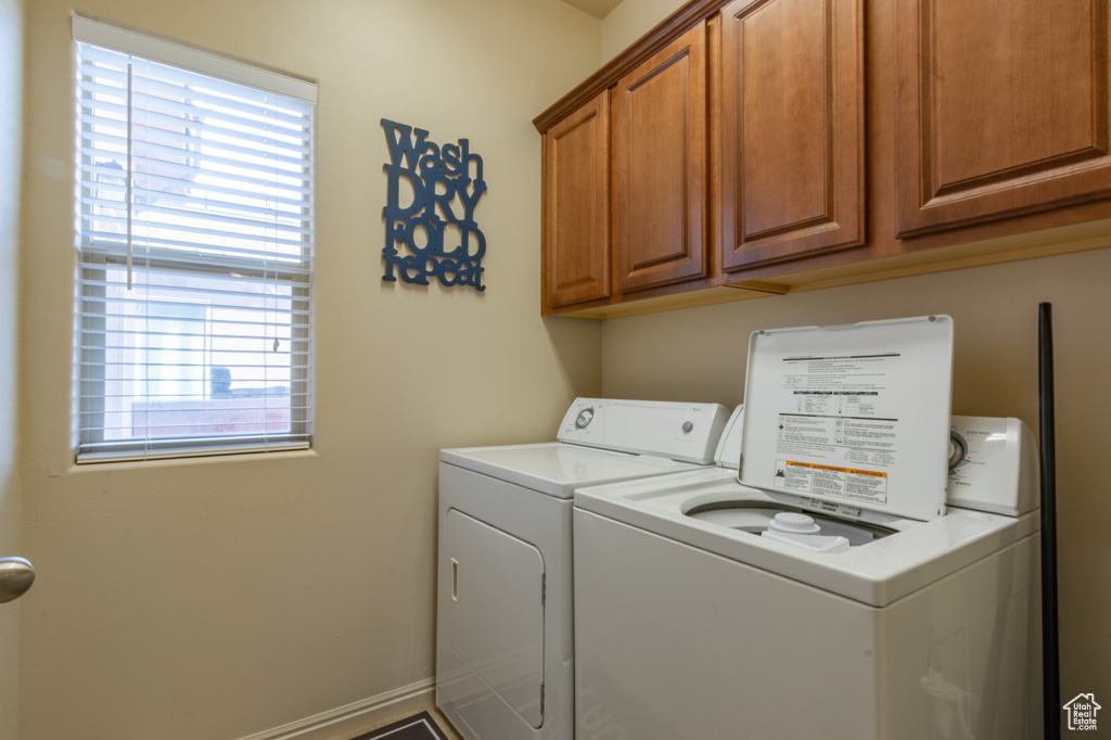 Laundry area with washer and dryer, cabinet space, and baseboards