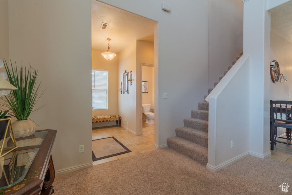 Entrance foyer featuring light tile patterned floors, visible vents, stairway, light carpet, and baseboards