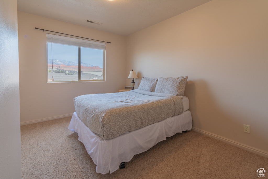 Bedroom featuring visible vents, light carpet, and baseboards