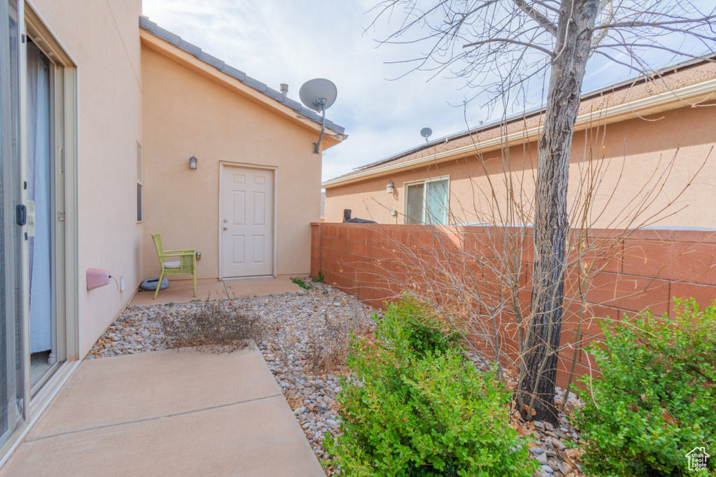 Property entrance with stucco siding, a patio, and fence