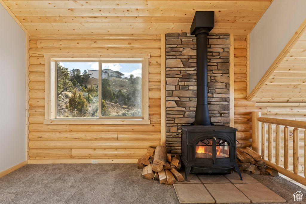 Room details with a wood stove, baseboards, and carpet flooring