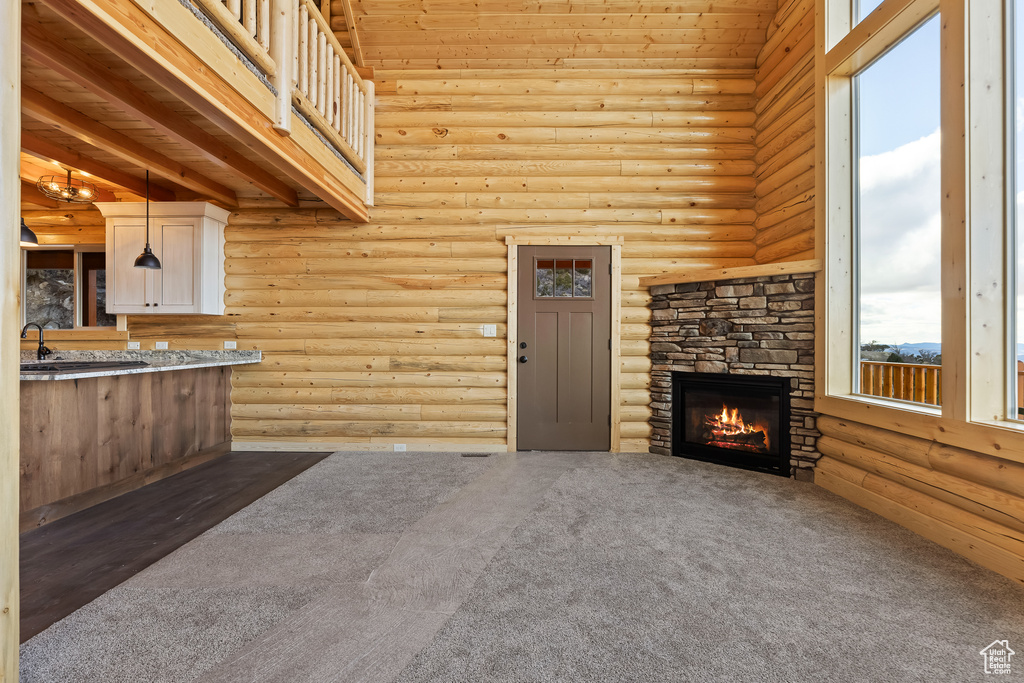 Interior space with rustic walls, a sink, a stone fireplace, and a high ceiling