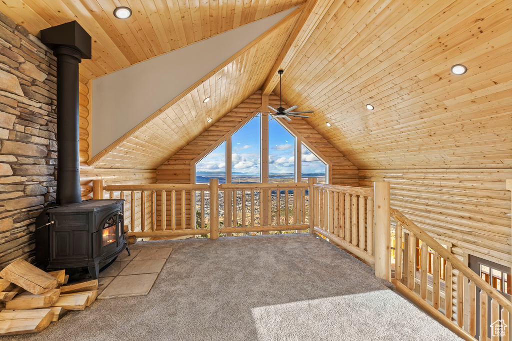 Unfurnished living room with lofted ceiling with beams, wood ceiling, rustic walls, and a wood stove