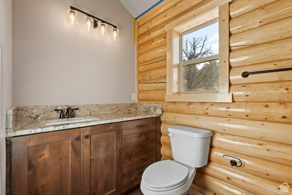 Half bath with toilet, vaulted ceiling, and vanity