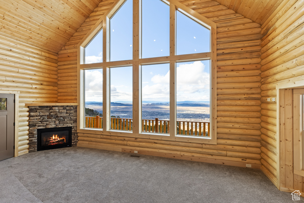 Unfurnished living room with high vaulted ceiling, a stone fireplace, and wooden ceiling