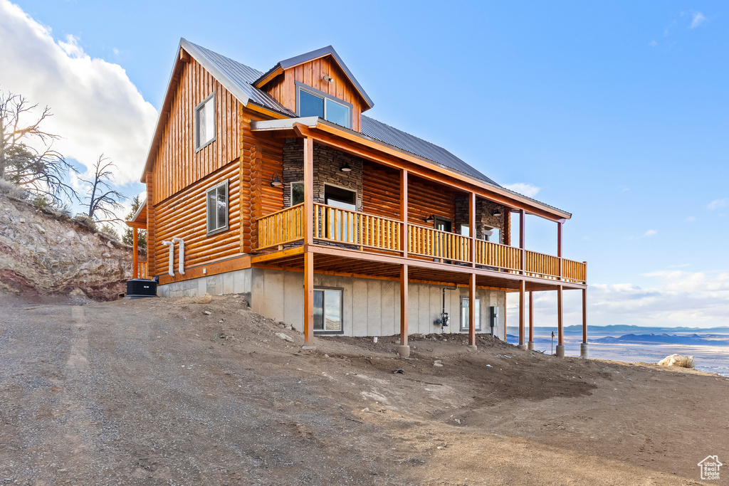 Exterior space with log siding, a deck, central AC unit, and metal roof