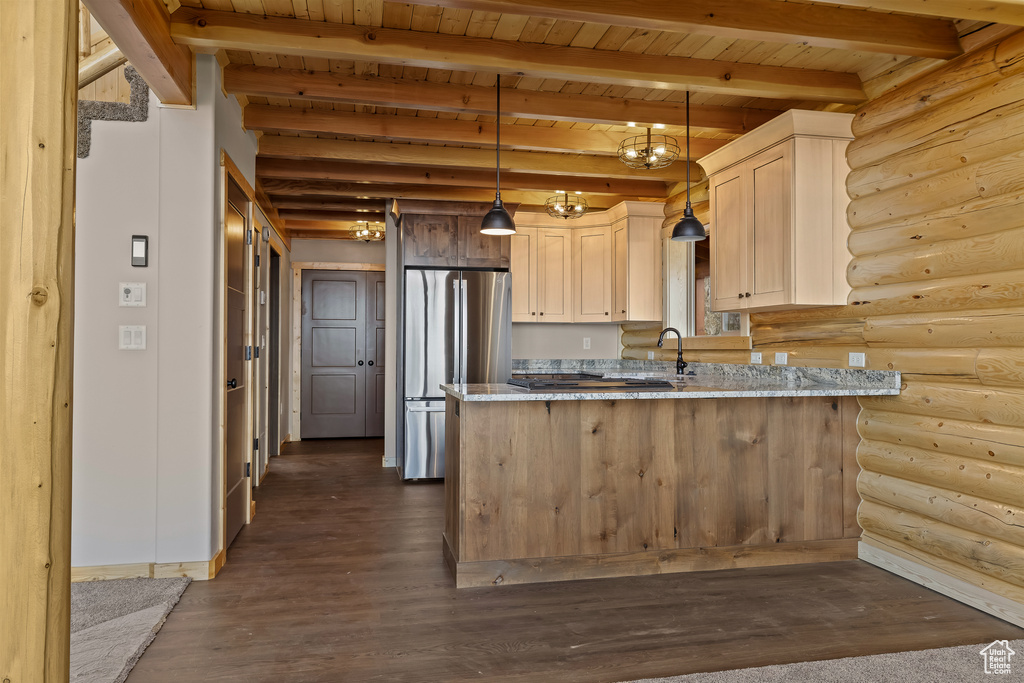 Kitchen featuring dark wood-style floors, beam ceiling, decorative light fixtures, freestanding refrigerator, and a peninsula