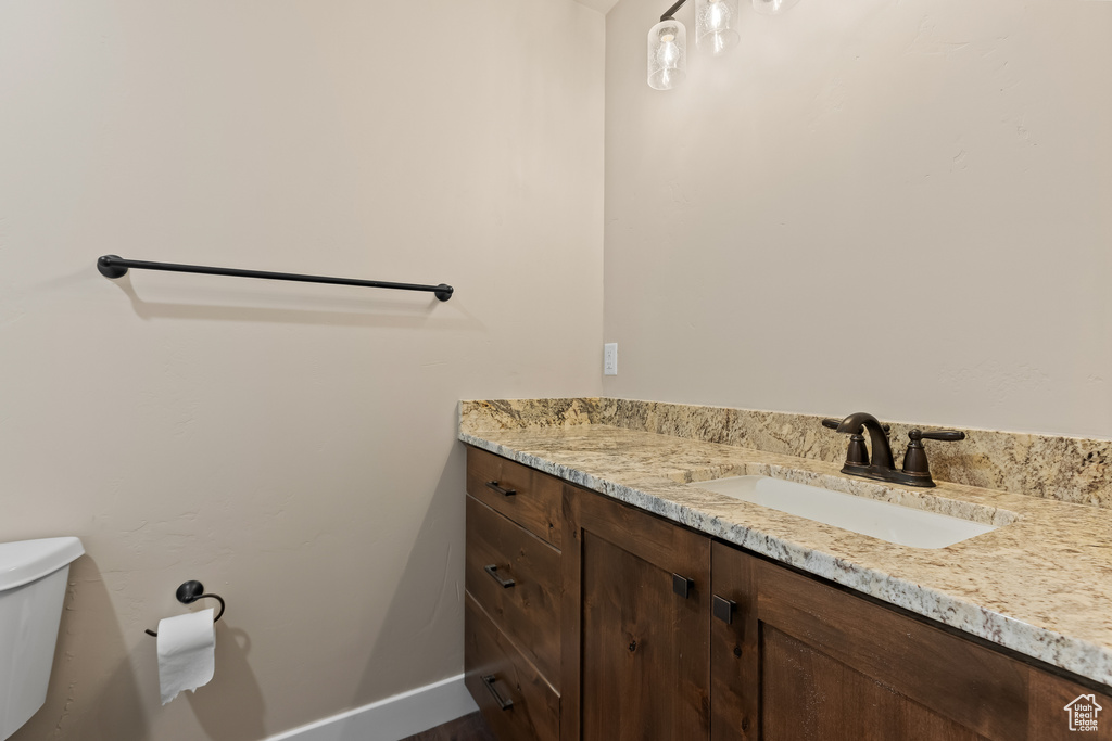 Half bathroom with toilet, baseboards, and vanity