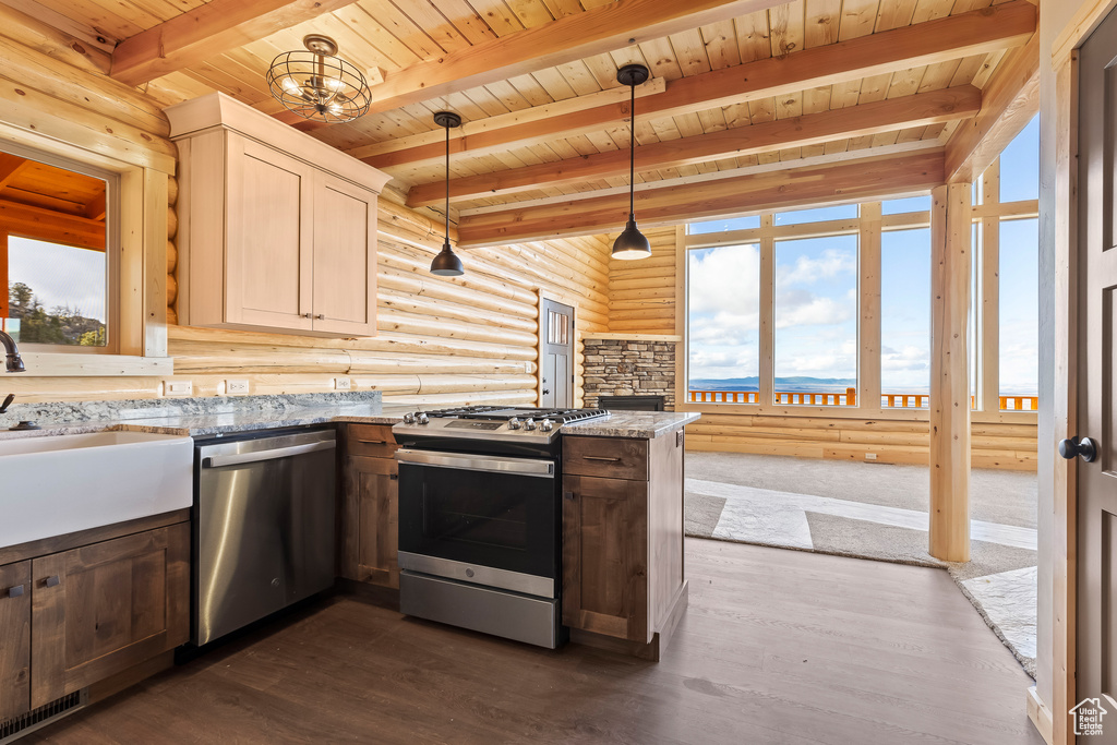 Kitchen featuring dark wood-style floors, appliances with stainless steel finishes, light stone countertops, pendant lighting, and a sink