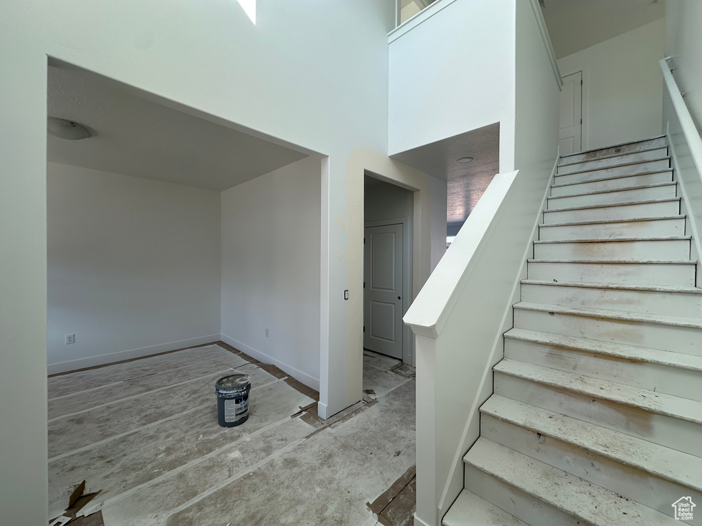 Stairway featuring a high ceiling and baseboards