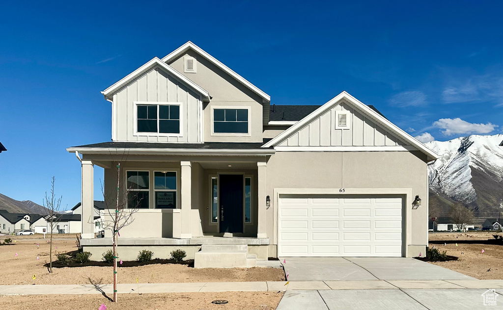 Modern farmhouse featuring an attached garage, board and batten siding, driveway, a mountain view, and covered porch