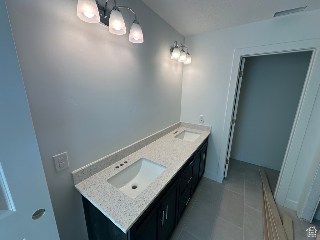 Bathroom with double vanity, a sink, baseboards, and tile patterned floors