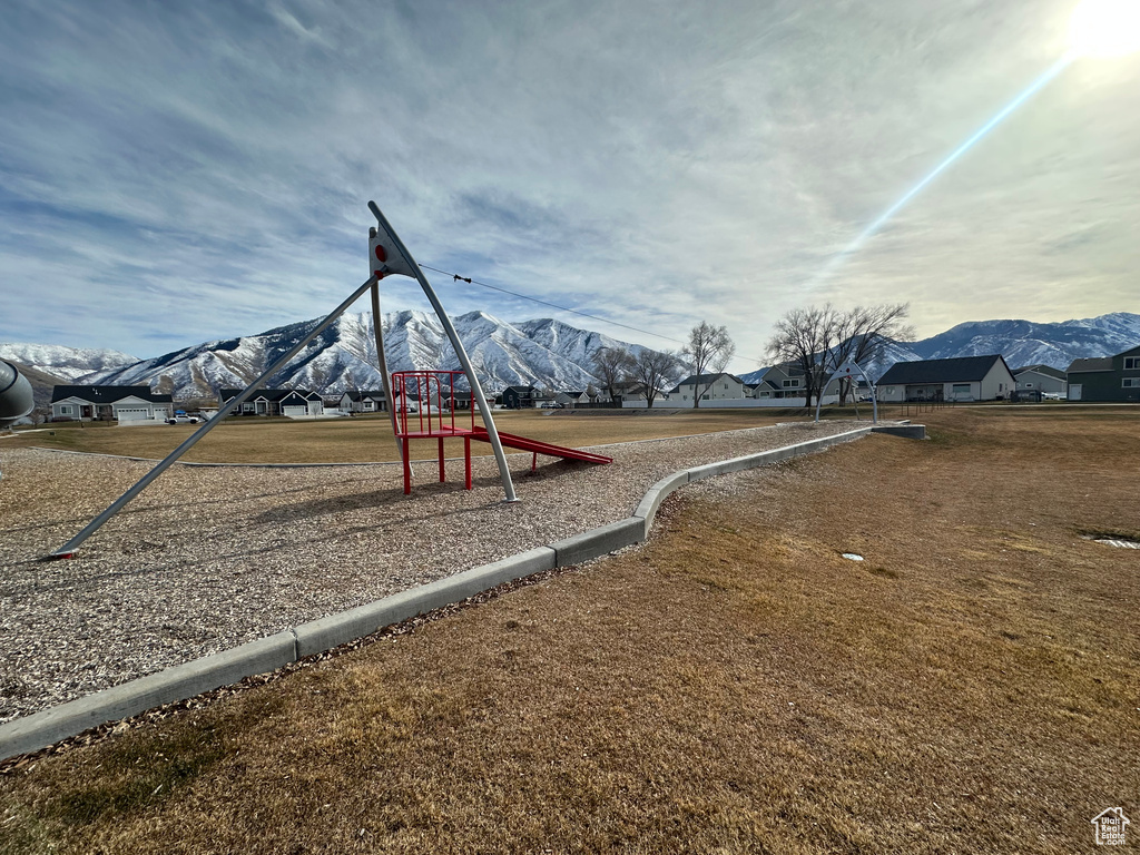 Community play area with a mountain view and a yard