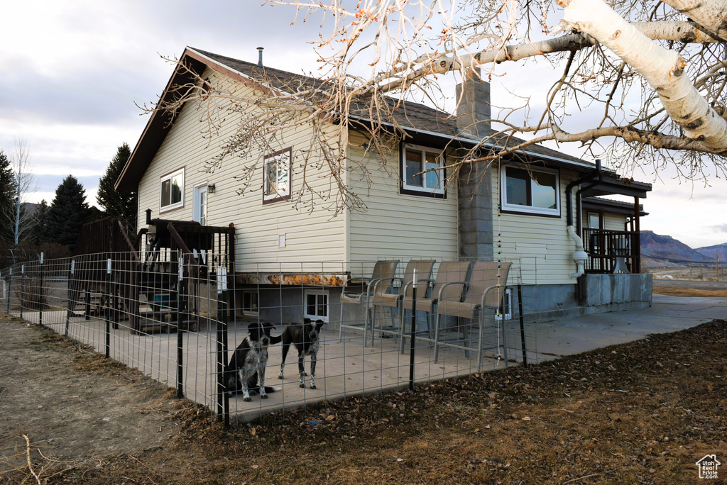 Back of property with a patio, a chimney, and a mountain view