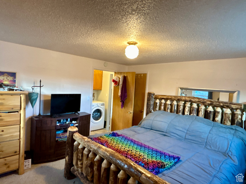 Bedroom with washer / clothes dryer, light colored carpet, and a textured ceiling