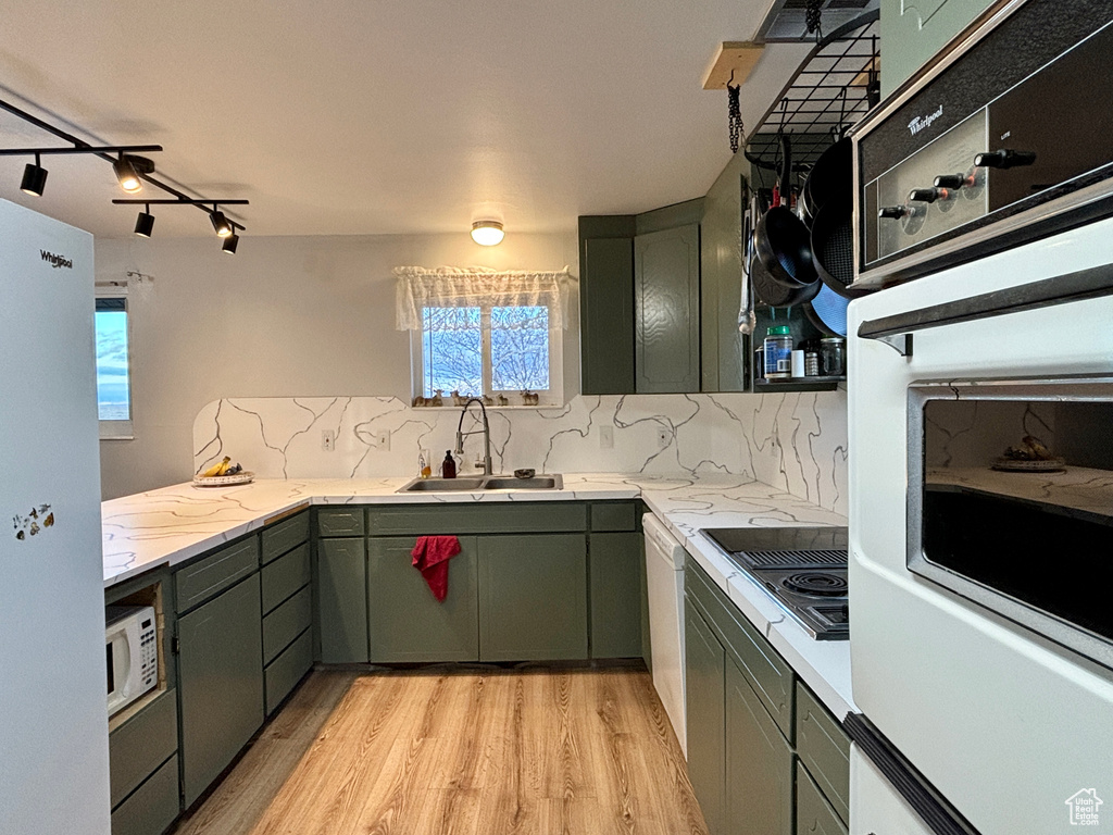 Kitchen with light countertops, white appliances, a sink, and tasteful backsplash